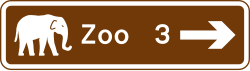 UK brown tourist sign showing a junction ahead leading to a tourist attraction