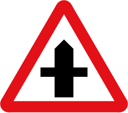 UK crossroads warning sign: a red-bordered triangle with a black upright line crossed by a horizontal line