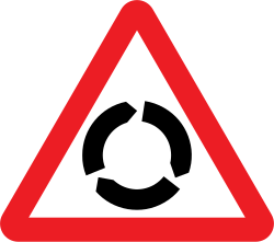 UK roundabout warning sign: a red-bordered triangle with three black arrows curving round in a circle